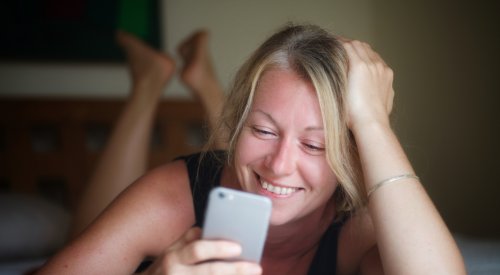 Kvinne ser smilende på mobilen sin. Kvinne ser smilende på mobilen sin.