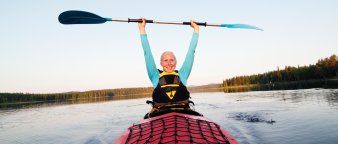 Smilende kvinne holder åren opp i været mens hun padler kajakk. Smilende kvinne holder åren opp i været mens hun padler kajakk.