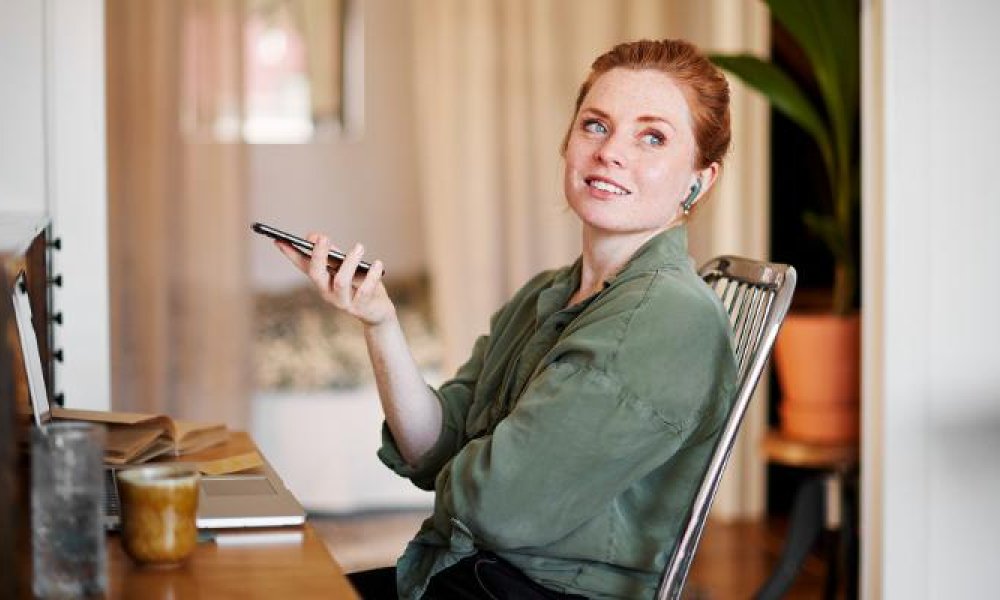 Dame ved kontorpult snakker i telefonen. Foto: Johner