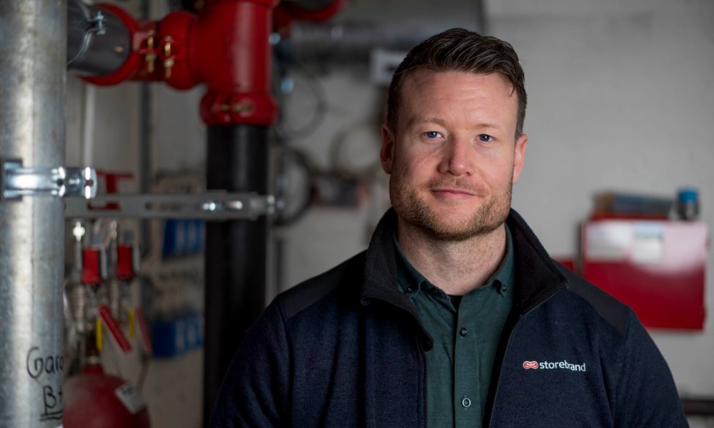 Sondre Zakariassen, risikoingeniør i Storebrand, foran rørinnstallasjoner.