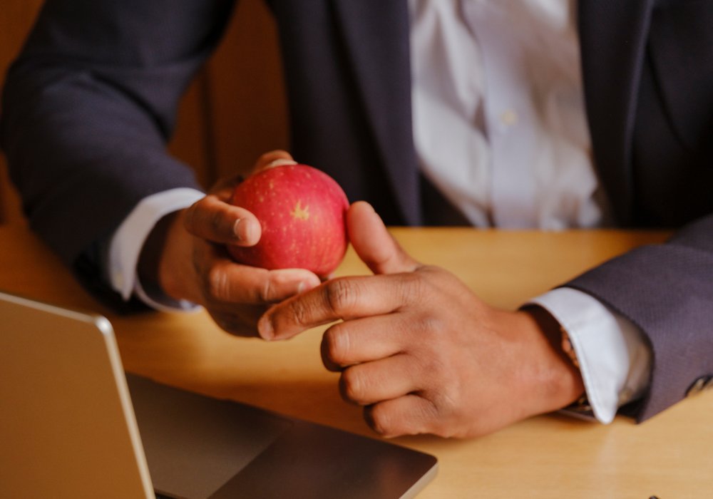 Nærfoto av en mann i dress som holder et rødt eple mens han ser på pc-en sin. Nærfoto av en mann i dress som holder et rødt eple mens han ser på pc-en sin.