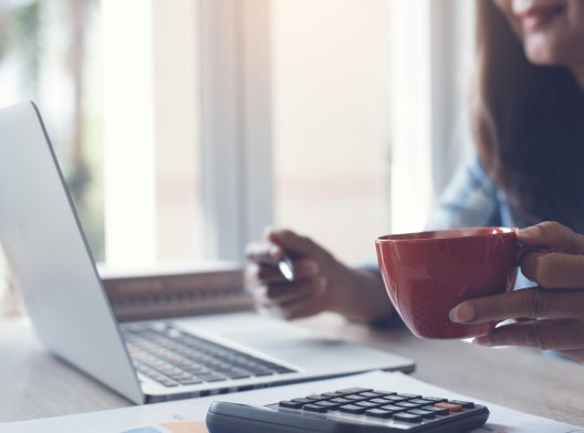 Illustrasjonsfoto: dame holder rød kaffekopp ved pc-en Illustrasjonsfoto: dame holder rød kaffekopp ved pc-en
