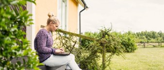 Dame som sitter på trappen utenfor huset sitt og ser på en PC-skjerm. Dame som sitter på trappen utenfor huset sitt og ser på en PC-skjerm.