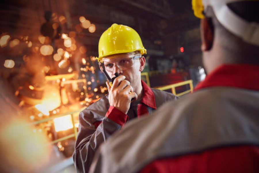 Industriarbeider i gul hjelm og walkie-talkie Industriarbeider i gul hjelm og walkie-talkie