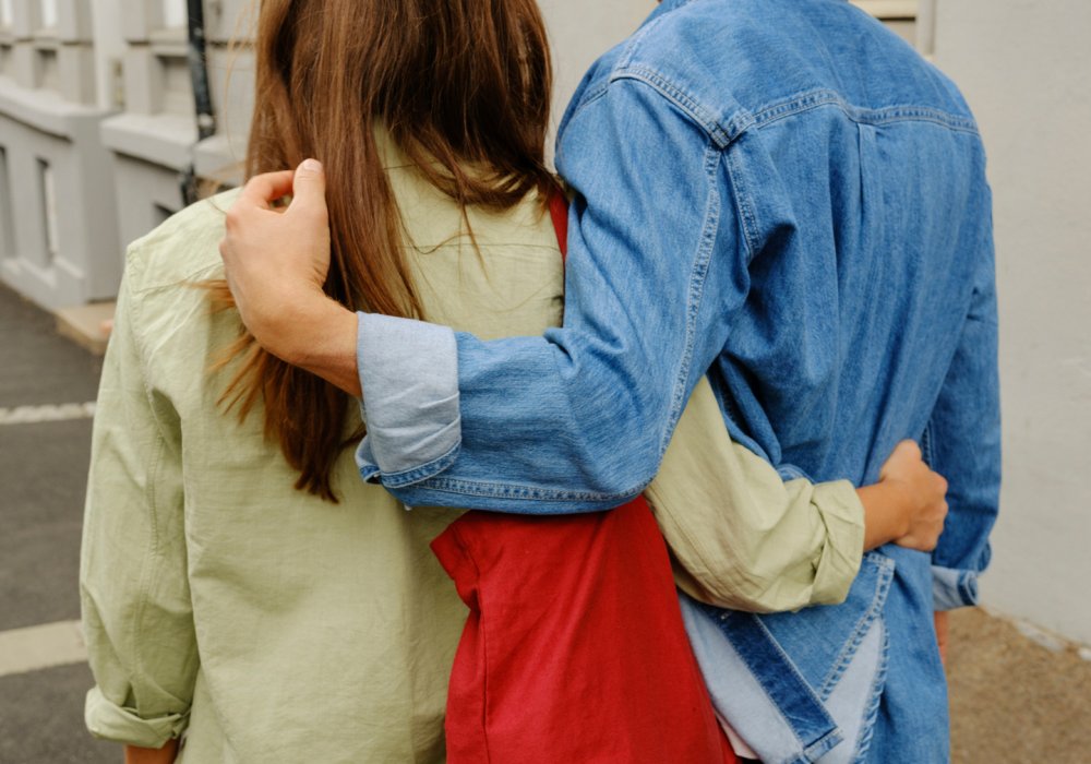 Foto av et ungt par som holder rundt hverandre mens de går ned en gate