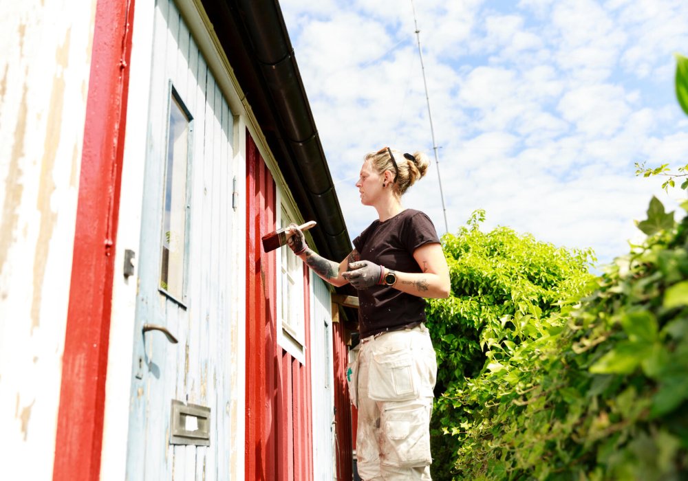 Illustrasjonsfoto: En kvinne maler huset rødt.