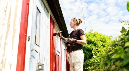 Illustrasjonsfoto: En kvinne maler huset rødt. Illustrasjonsfoto: En kvinne maler huset rødt.