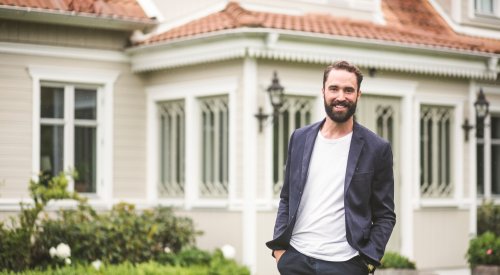 Illustrasjonsfoto: En mann med blazer står foran et stort hus. Illustrasjonsfoto: En mann med blazer står foran et stort hus.