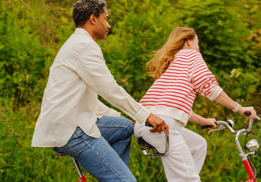 Foto av en mann og en dame som sykler på en rød tandemsykkel