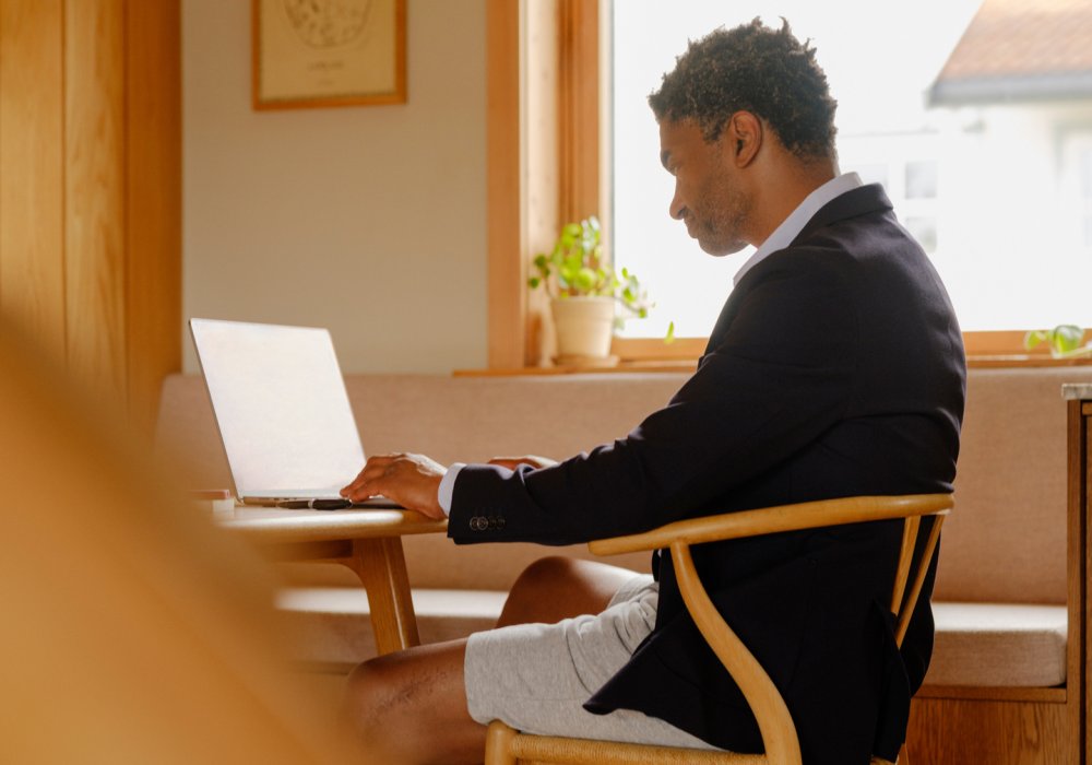 Foto bakfra av en mann som sitter å trykker på pc-en sin