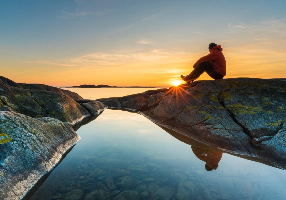 Illustrasjonsfoto: Mann som sitter på et berg i solnedgangen