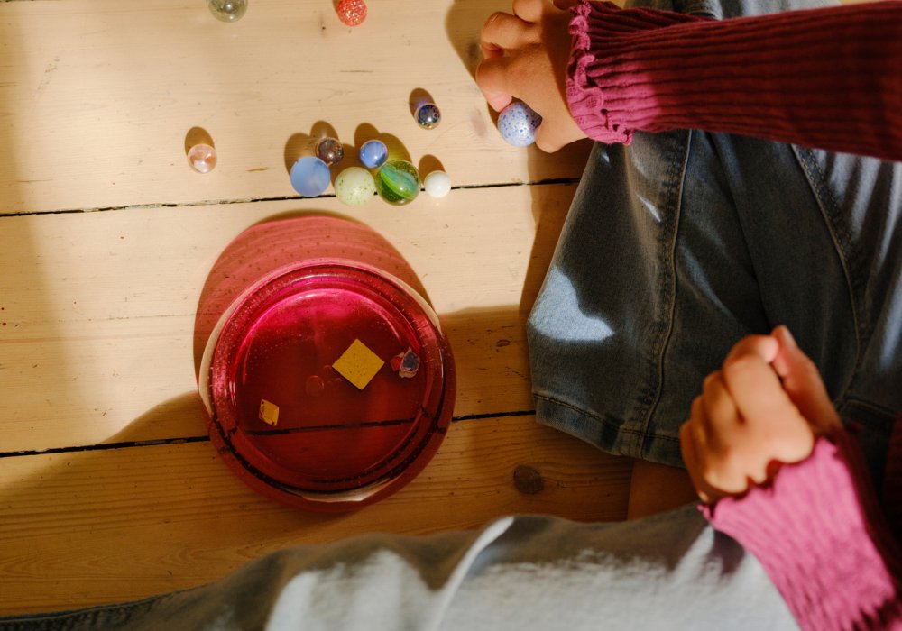 Barn som leker med klinkekuler på stuegulvet