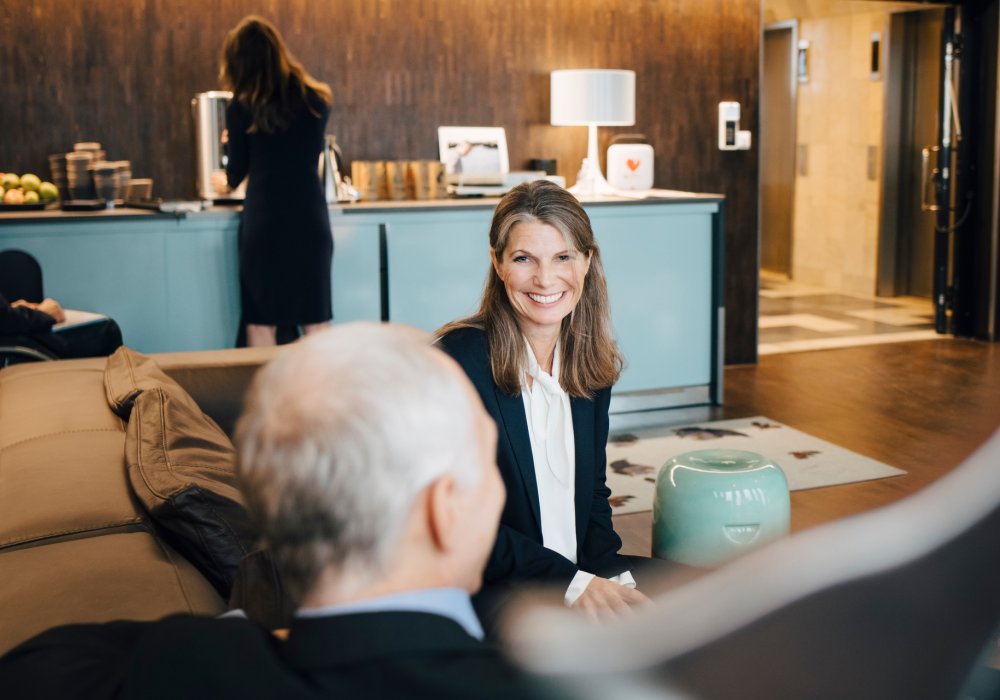 Illustrasjonsfoto: Dame prater med mann som sitter med ryggen til på et kontor. 