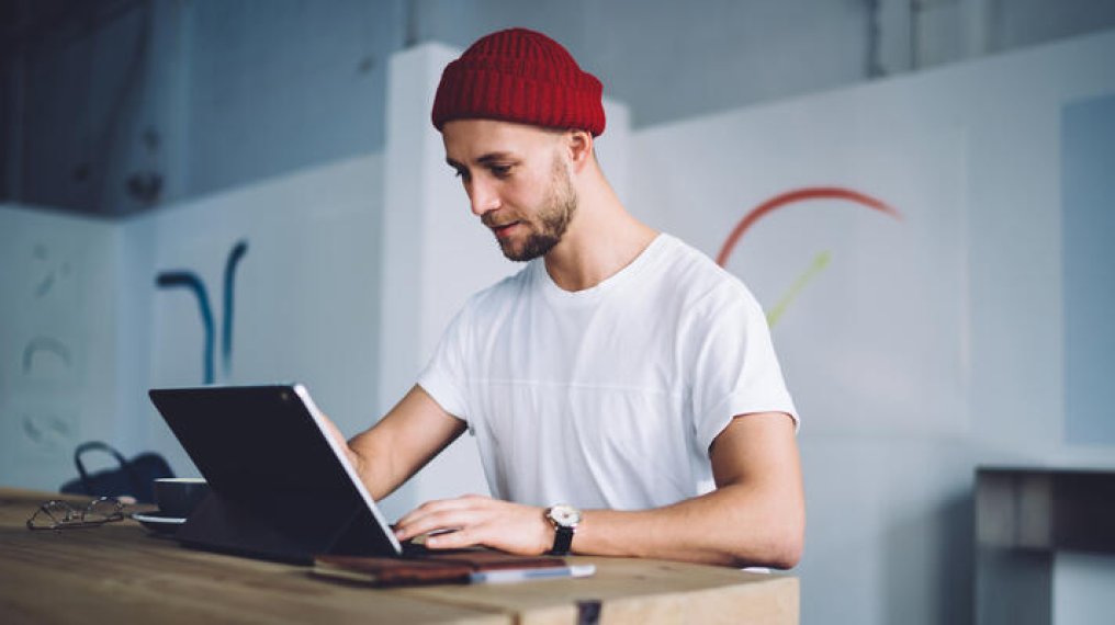 Mann med rød lue som sitter ved en PC. Mann med rød lue som sitter ved en PC.