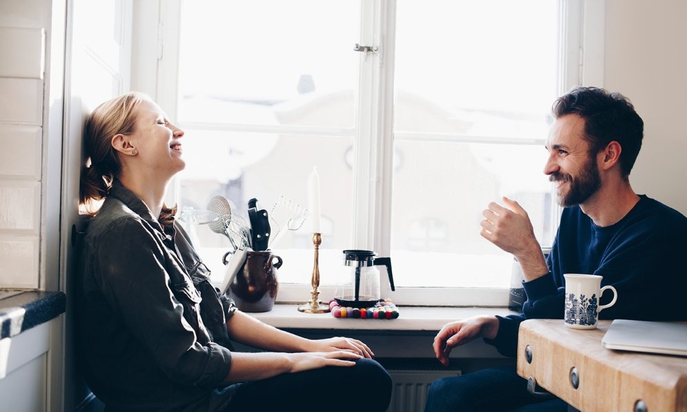 Illustrasjonsfoto: Par drikker kaffe og prater ved kjøkkenvinduet. 