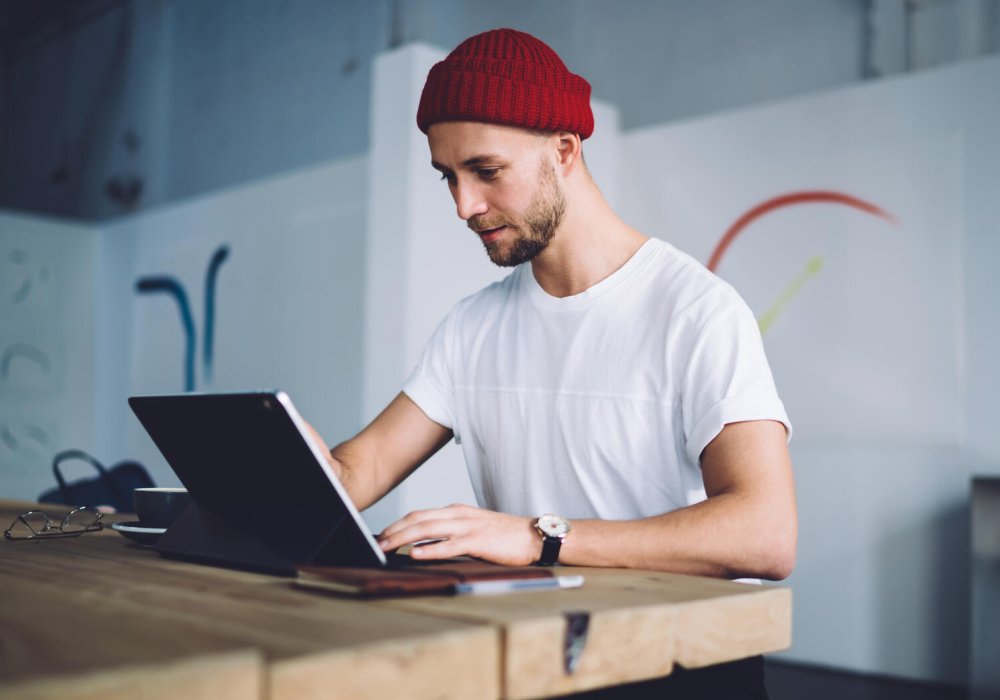 Illustrasjonsfoto: Mann med rød lue sitter foran en laptop.