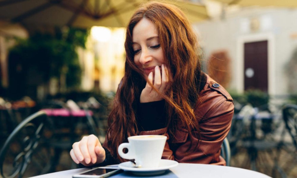 Illustrasjonsfoto: Dame på cafe med kaffekopp og mobiltelefon