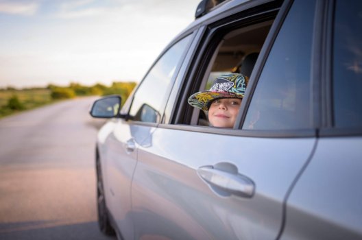 liten jente med hatt i bilvindu