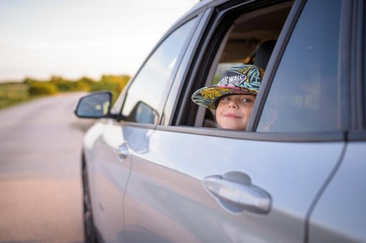 liten jente med hatt i bilvindu