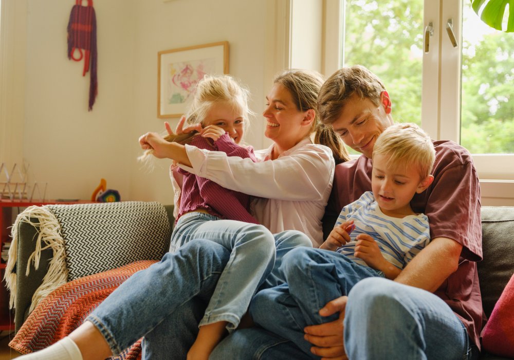 En mor og far med sin datter og sønn i sofaen