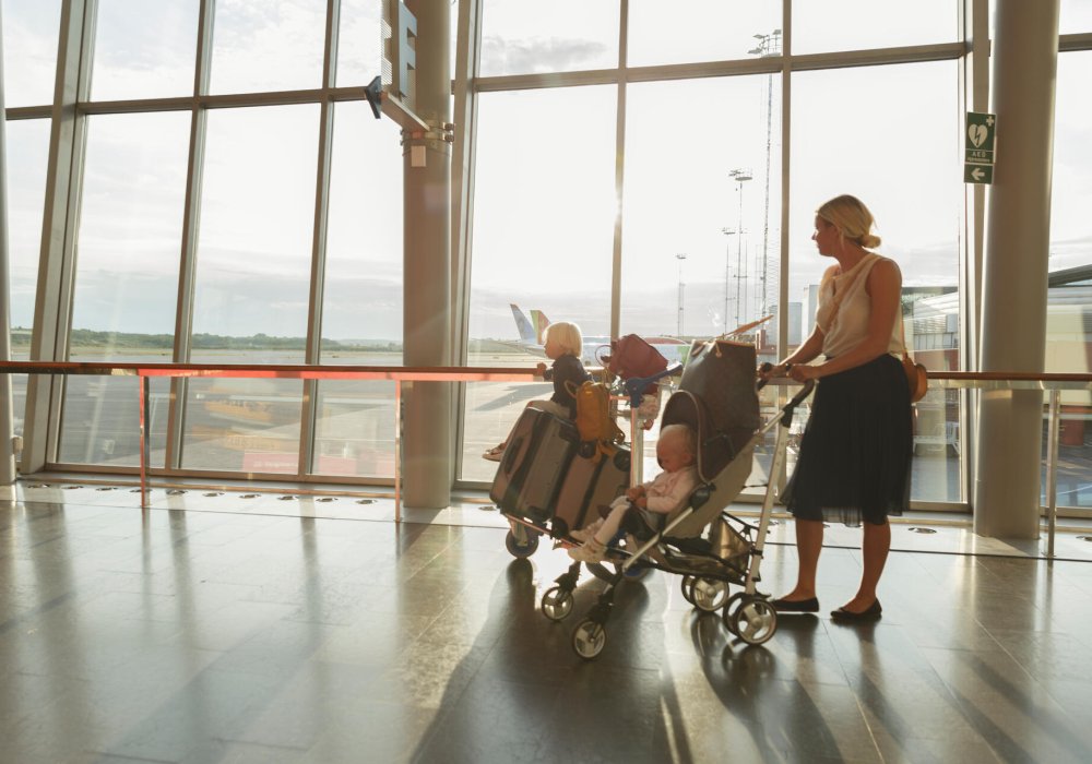 Mor med to barn på en flyplass. Illustrasjonsfoto.