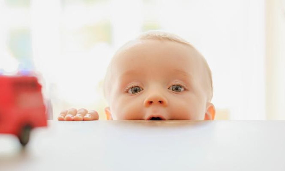 Baby som titter over bordkanten.