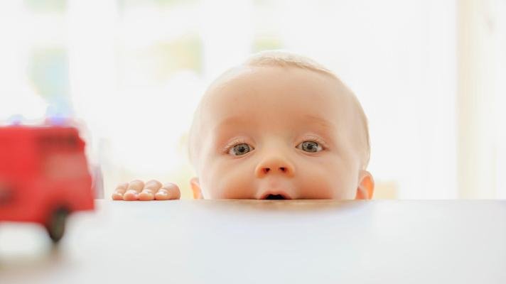 Baby som titter over bordkanten.