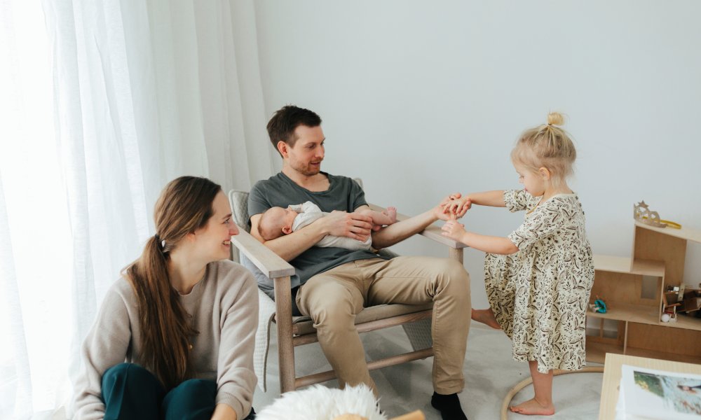 Familie med nyfødt baby som sitter i en stue.