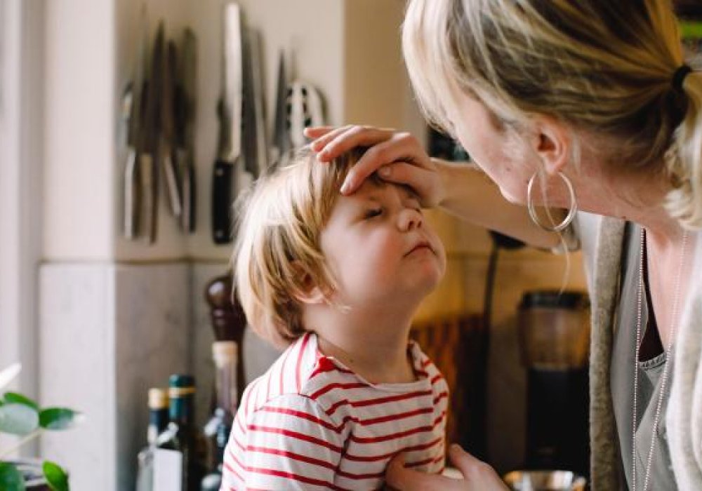 Mor sammen med sykt barn på kjøkkenet.