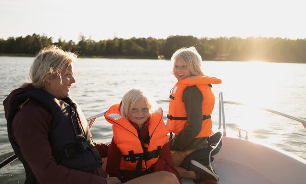 Mor med to barn ute i båt en fin sommerkveld.