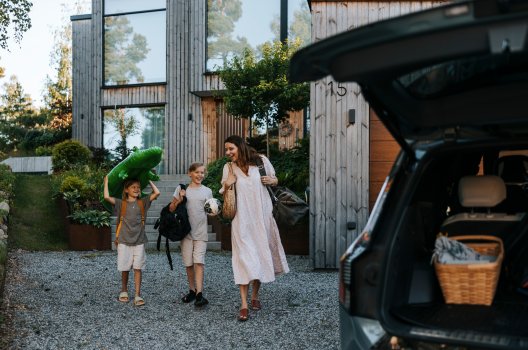 Mor og sine to sønner pakker bilen som står i oppkjørselen