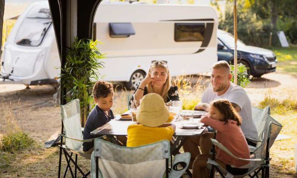 Familie med tre barn på sommerferie med campingvogn.