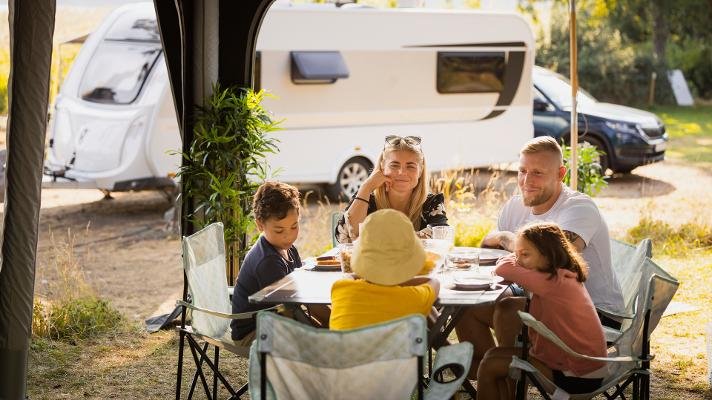 Familie med tre barn på sommerferie med campingvogn.