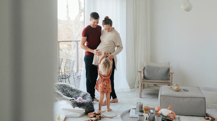 Gravid dame i stue med familie rundt seg. 
