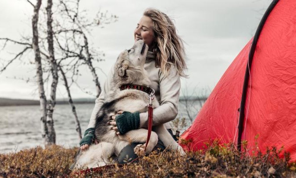Dame på tur ute om høsten med hunden sin.