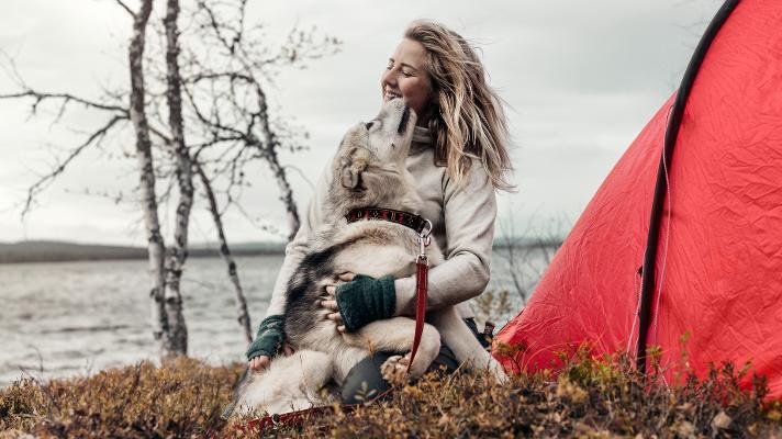 Dame på tur ute om høsten med hunden sin.