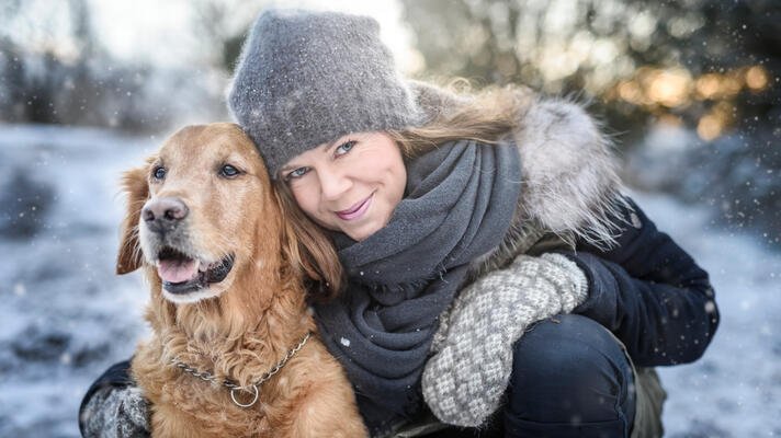 Dame ute i snøen sammen med hunden sin.