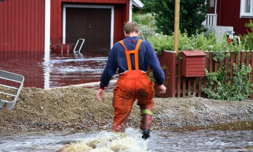 Mann som vasser ute under kraftig regn.