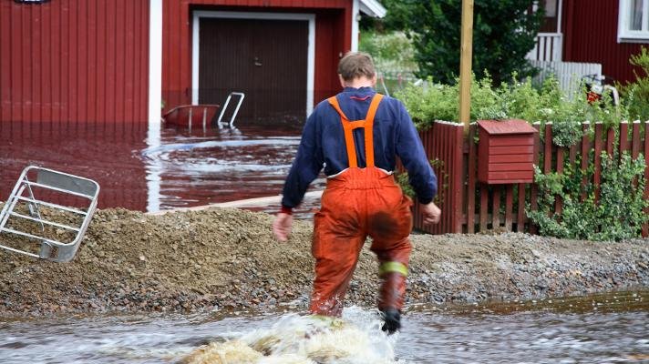 Mann som vasser ute under kraftig regn.