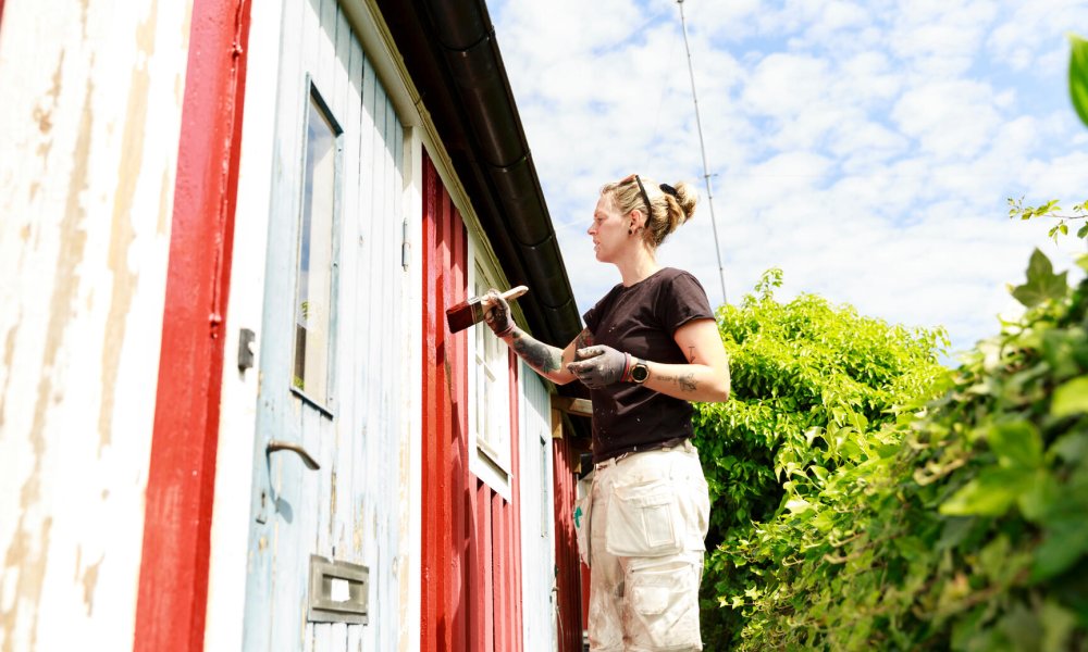 Illustrasjonsfoto: En kvinne maler huset rødt.