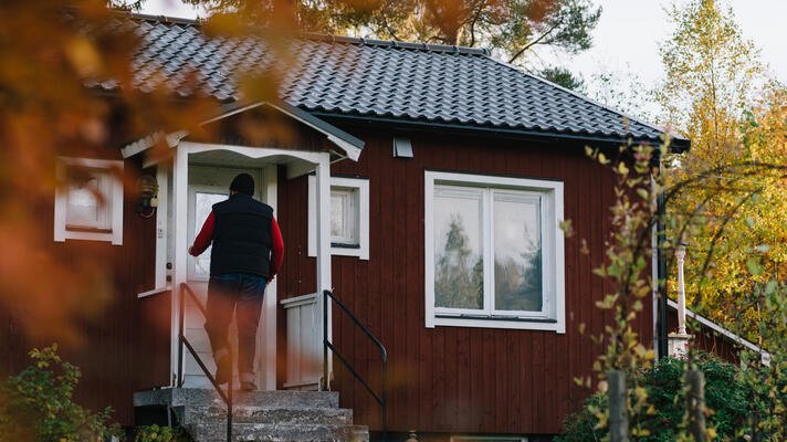 Mann som går inn i et rødt hus.