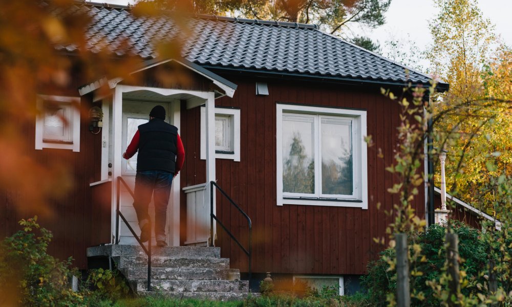 Mann som låser opp døren til en hytte.