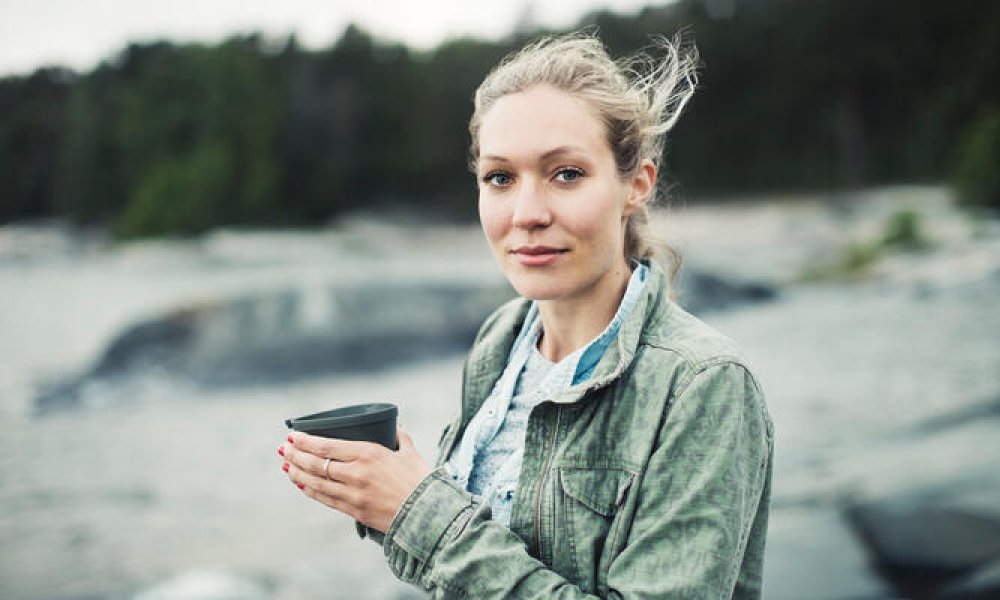 Illustrasjonsfoto: ung kvinne på tur med kaffekoppen i hånden.