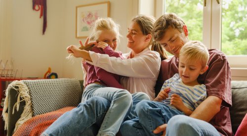 En mor og far med sin datter og sønn i sofaen