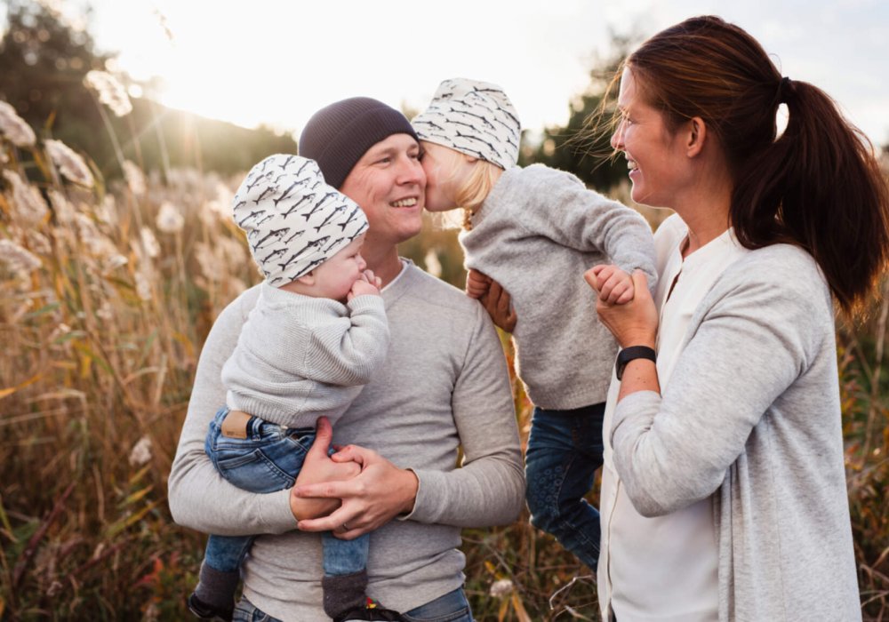 Illustrasjonsfoto: Familie  med mor, far og to små barn utendørs om høsten. 