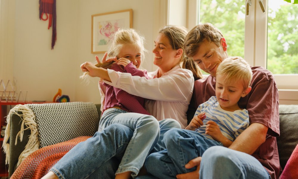 En mor og far med sin datter og sønn i sofaen