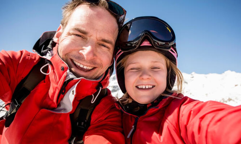 Far og datter på skitur i solen.