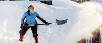 Dame som står på et hyttetak og måker snø om vinteren. Dame som står på et hyttetak og måker snø om vinteren.