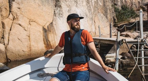 Mann som sitter i en båt en fin sommerdag.