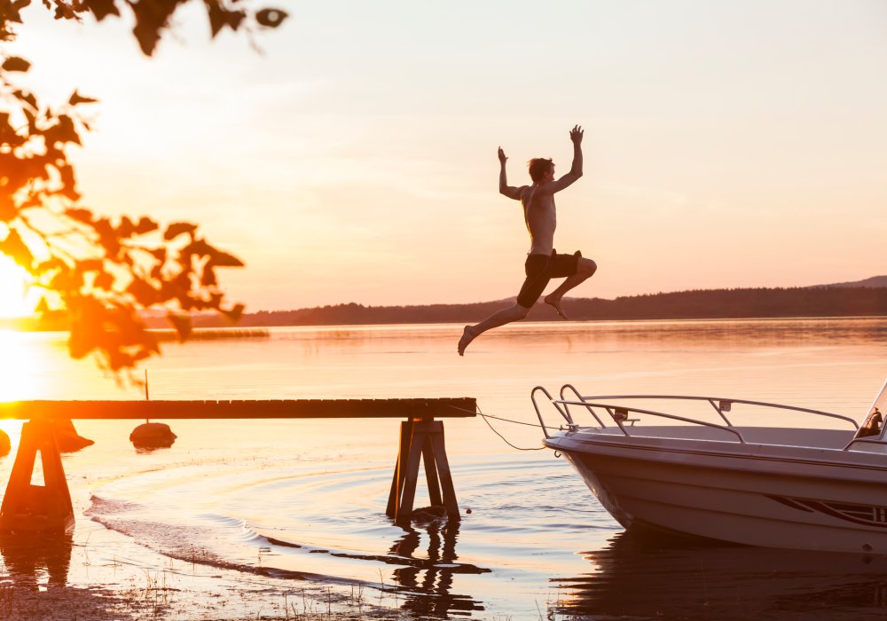 Illustrasjonsfoto: Mann hopper i havet fra brygge i solnedgang. 